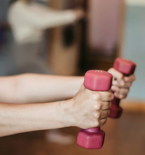 person holding pink and white dumbbells