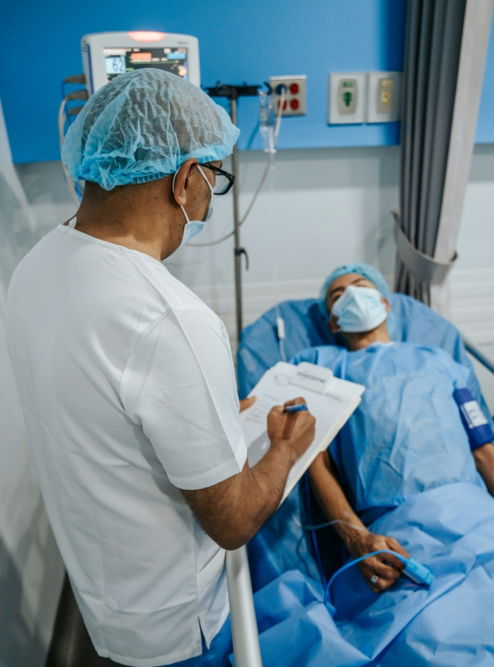 a man in a hospital bed writing on a clipboard
